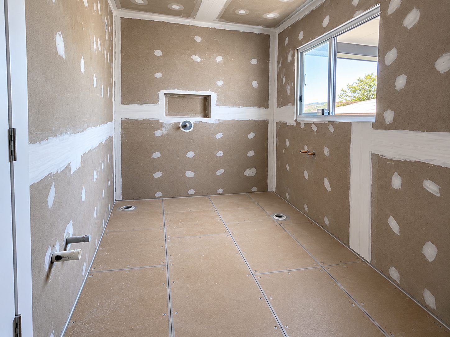 Bathroom with fibre cement sheeting, shower niche and floor wastes, ready for waterproofing before tiling