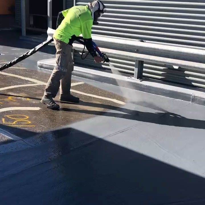 Applicator spraying membrane over a carpark deck and kerb